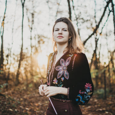 uśmiechnięta kobieta z batutą w lesie